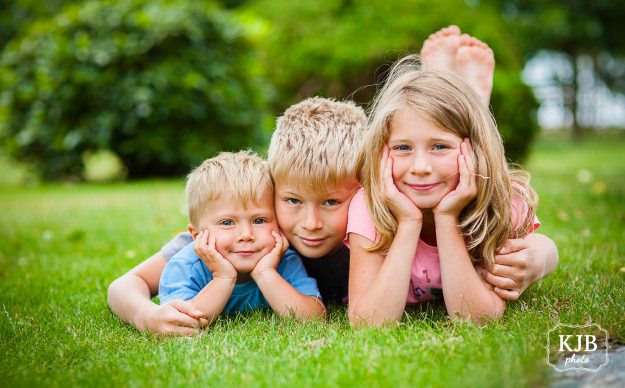Jarní focení dětí - tři děti leží na trávě